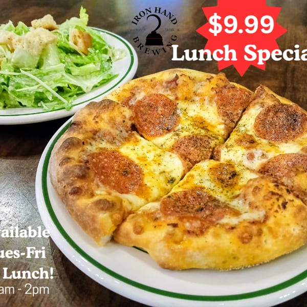 Pepperoni pizza and a side salad on a wooden table, advertising Iron Hand Brewing's lunch specials.